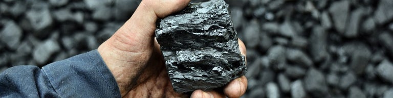 Hand holding coal in coal mine