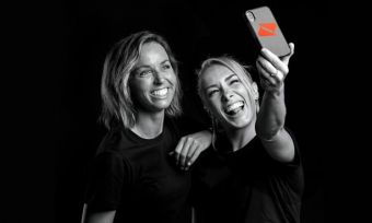 Two blonde women taking a selfie with a Boost Mobile phone