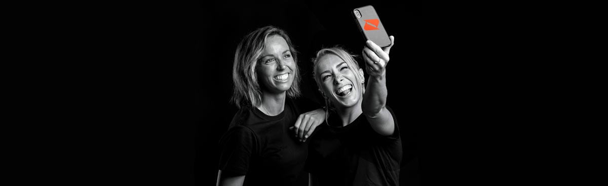 Two blonde women taking a selfie with a Boost Mobile phone