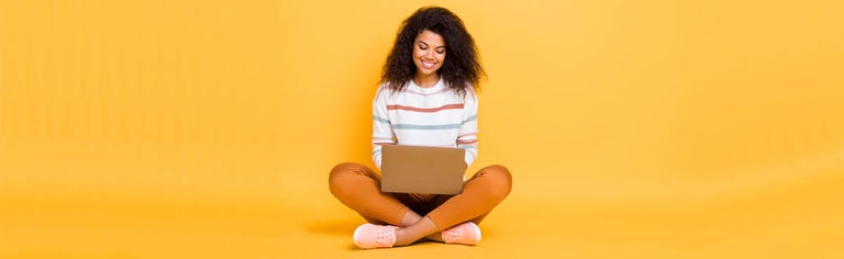 Happy woman using laptop against yellow background