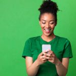 Smiling attractive woman in green using mobile phone