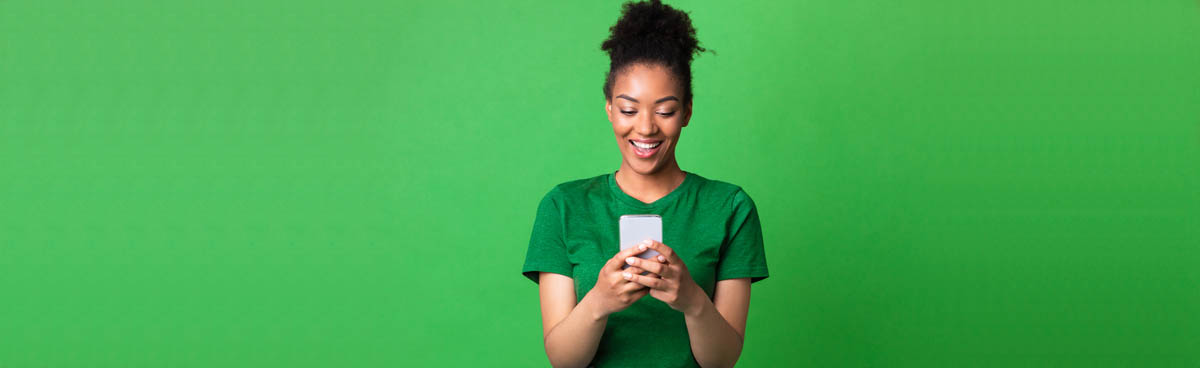 Smiling attractive woman in green using mobile phone