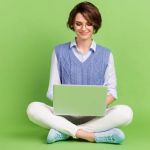 Woman on laptop with green background