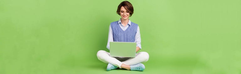 Woman on laptop with green background