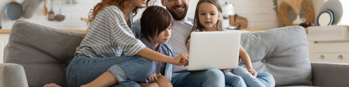 A family sitting on a couch using a laptop