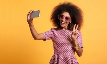 Young woman in red dress taking selfie with peace sign