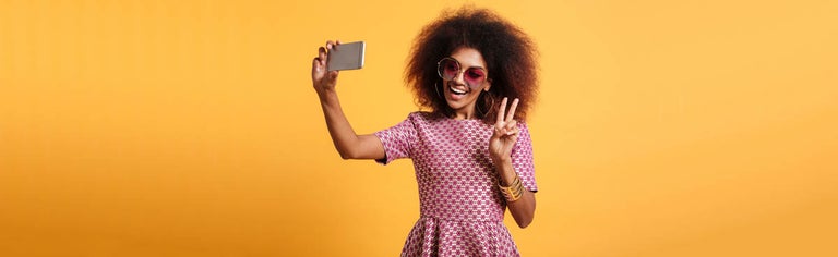 Young woman in red dress taking selfie with peace sign