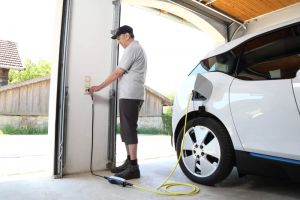 Man charging electric car at home