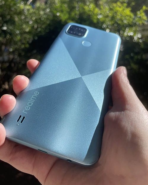 Back of Realme C21 phone in blue being held