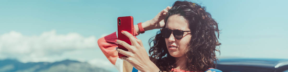 Woman looking at phone trying to find network coverage outdoors