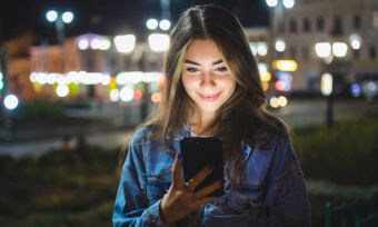 Woman using smartphone outdoors at night