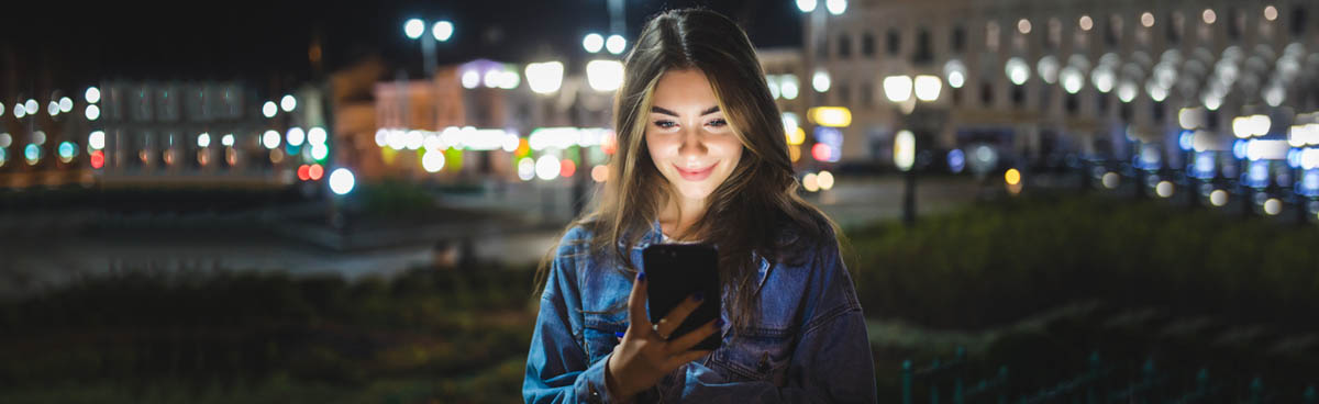 Woman using smartphone outdoors at night