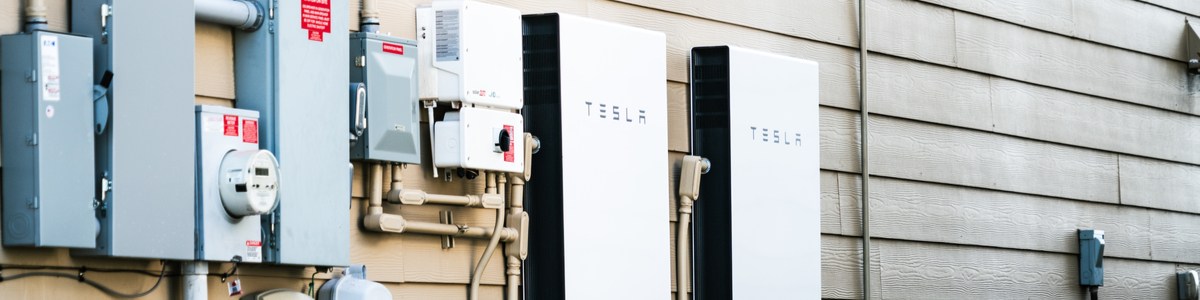 Tesla solar battery in home next to energy meter