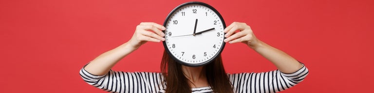 Woman holding clock over face signifying long wait times with red background
