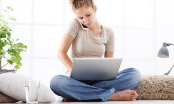 Young woman on phone and using laptop
