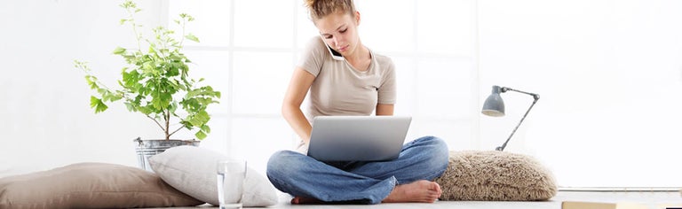 Young woman on phone and using laptop