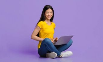 Smiling young woman using internet with purple background