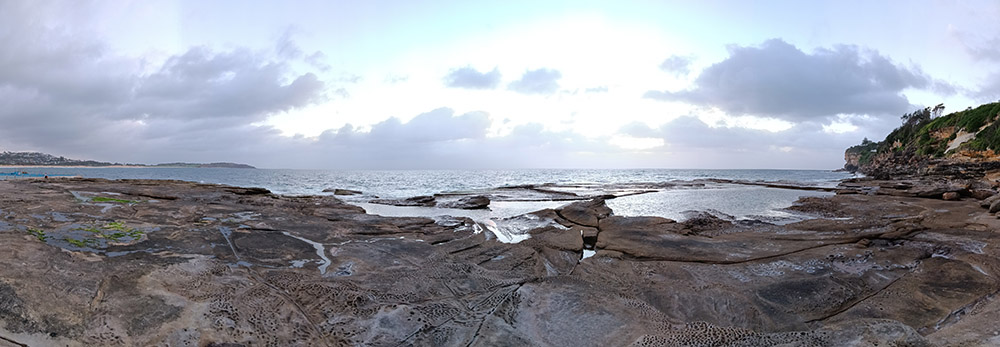 Panorama shot of rock pools and sunrise over ocean