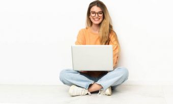 Young woman sitting cross legged using laptop