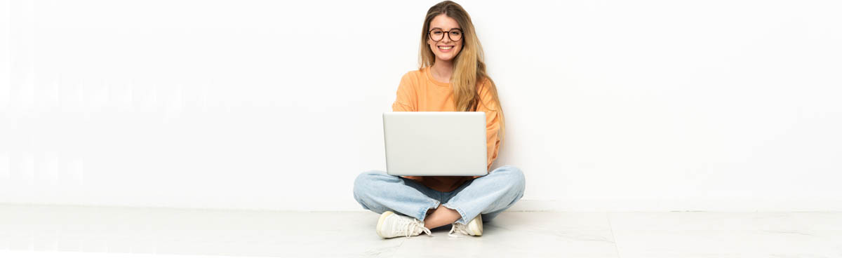 Young woman sitting cross legged using laptop