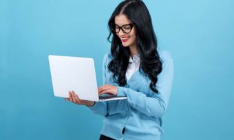 Happy young woman using laptop with blue background