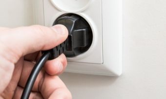 Hand plugging in electrical cord to socket