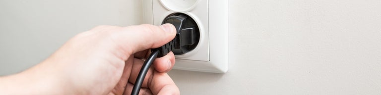 Hand plugging in electrical cord to socket