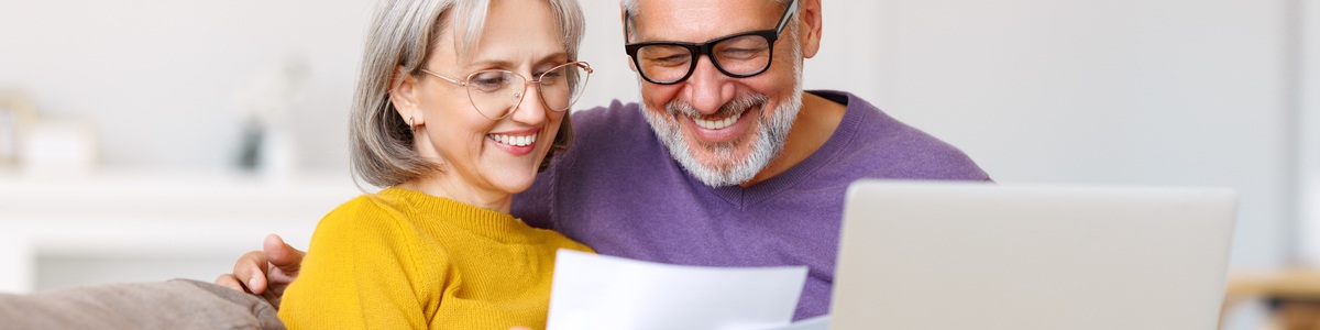 Old couple looking happily at their bills