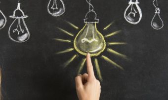 Woman pointing at light bulb on blackboard