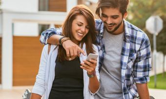 Young couple looking at mobile phone while walking down road