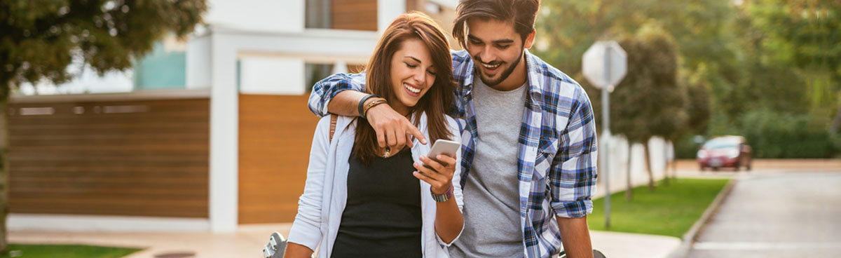 Young couple looking at mobile phone while walking down road