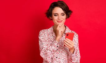 Woman against red background looking at red mobile phone