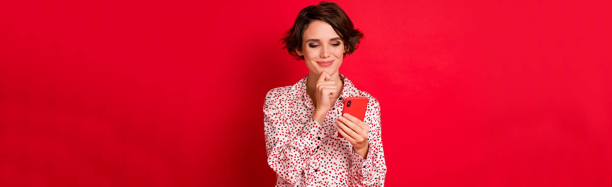 Woman against red background looking at red mobile phone