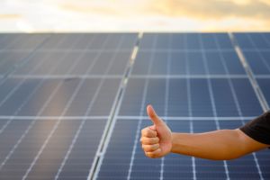 Man giving thumbs up in front of solar panels