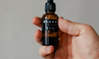 Hand holding beard oil bottle