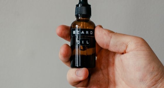 Hand holding beard oil bottle