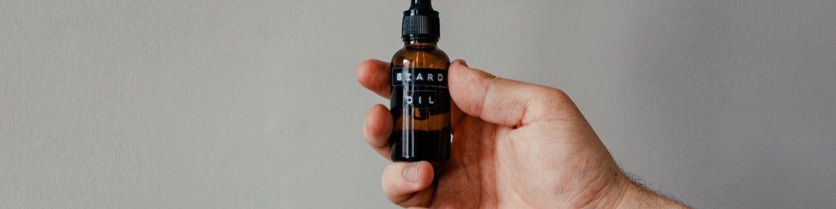 Hand holding beard oil bottle