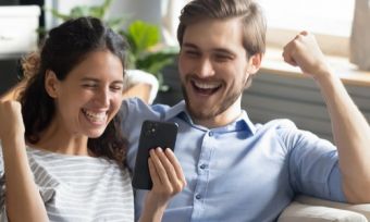 Couple happily staring at their phone, cheering