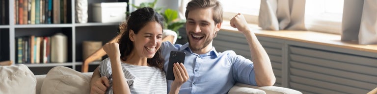 Couple happily staring at their phone, cheering