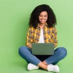 Young woman looking at computer against green background