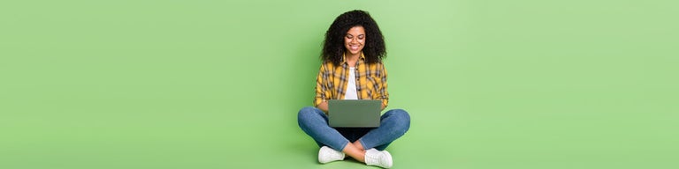 Young woman looking at computer against green background