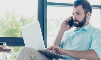 Man sitting in chair on phone with laptop