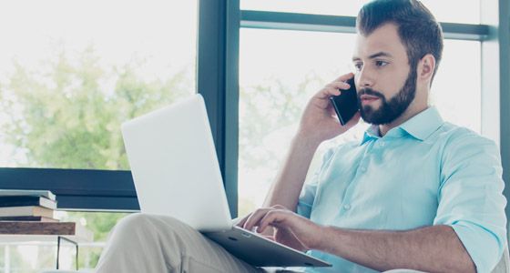Man sitting in chair on phone with laptop