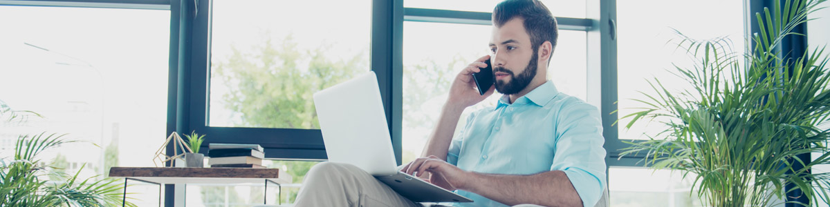 Man sitting in chair on phone with laptop