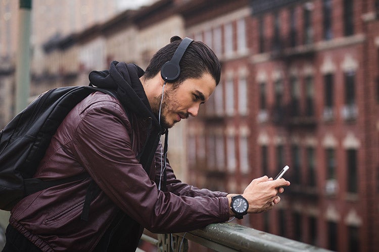 Man looking at phone while wearing headphones outside