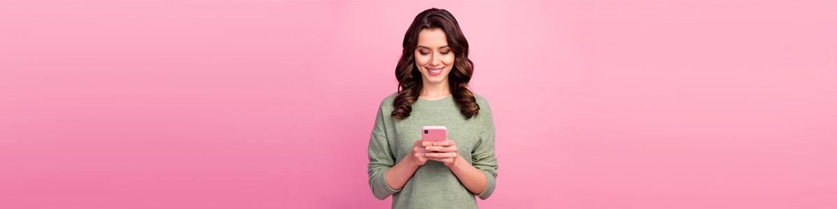 Woman looking at mobile phone against pink background