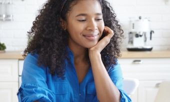 Woman smiling happily at computer screen.