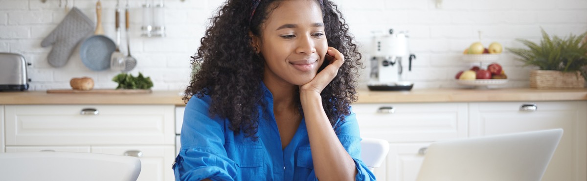 Woman smiling happily at computer screen.