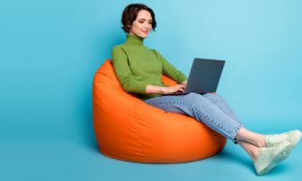 Woman sitting on bean bag looking at laptop