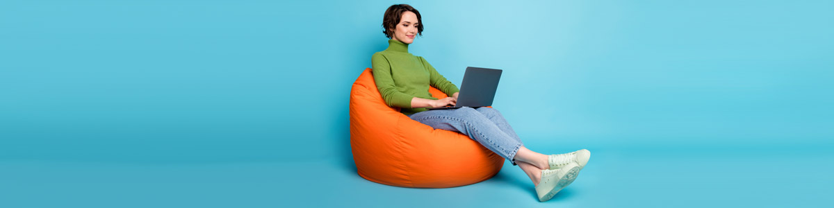 Woman sitting on bean bag looking at laptop